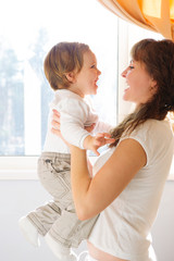 Mother holding little son against window