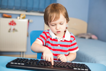 Little baby boy typing on computer keyboard