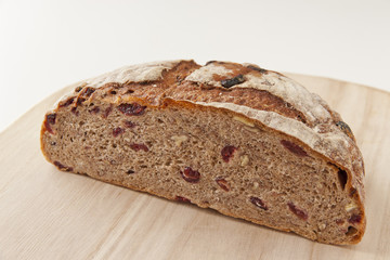 Round homemade whole grain bread with cranberry and walnut on a