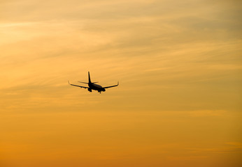 Fototapeta na wymiar Jetliner flying against red sunset sky