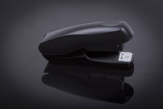photo  of a stapler on a black shiny background