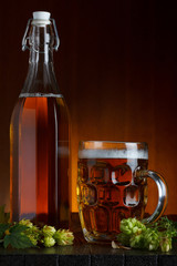 Beer still-life with fresh green hop on rustic wooden table