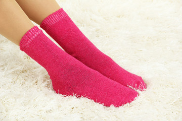 Female legs in colorful socks on  white carpet background