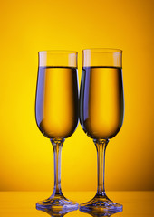 Two champagne flute glasses on yellow background