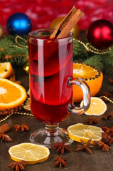 Fototapeta na wymiar Fragrant mulled wine in glass with spices and oranges around