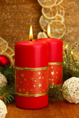 Two candles and christmas decorations, on golden background