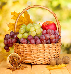 Naklejka na ściany i meble Grape in basket with nuts on wooden table