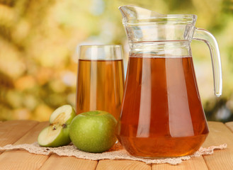 Full glass and jug of apple juice and apples