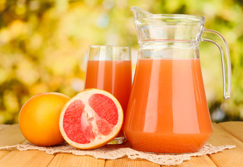 Full glass and jug of grapefruit juice and grapefruits