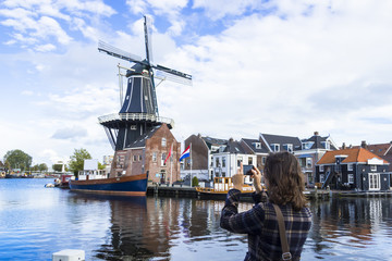Tourist girl is taking pictures of traditional Dutch windmill - 47729740