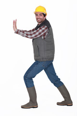 A construction worker pushing something invisible.