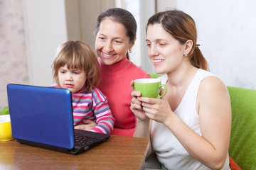 Fototapeta na wymiar Happy kobiet trzech pokoleń wygląda netbook