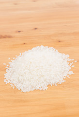 Fototapeta na wymiar Pile of raw rice on wooden table