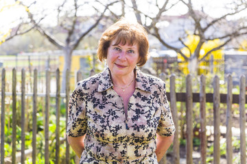 happy elderly woman is standing proud in her garden and smiles