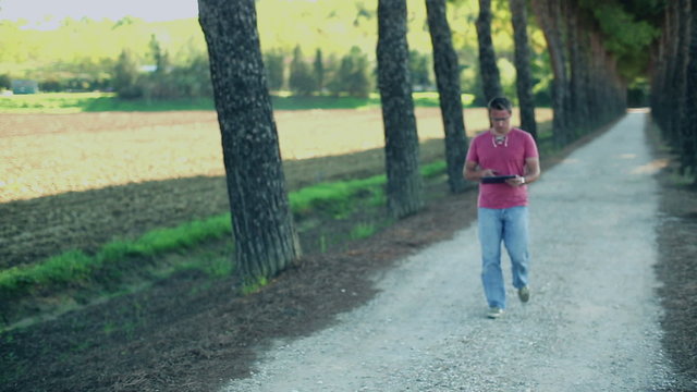 Young man with tablet computer standing in the park, crane shot