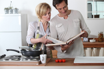 Couple cooking together with a recipe book