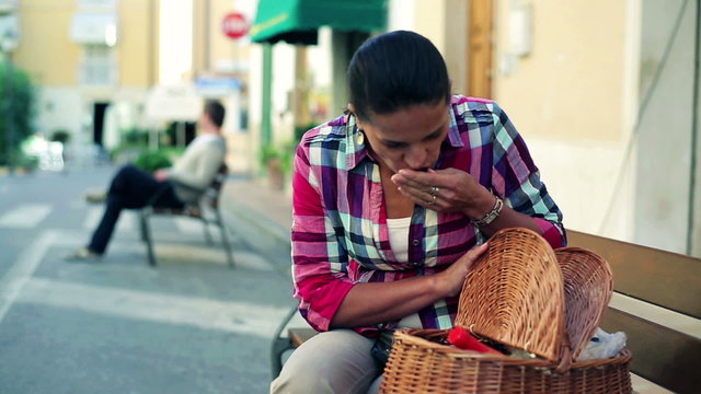 Young woman with basket full of shopping sitting on bench, stead