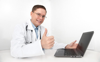 Doctor with laptop sitting in doctor's office