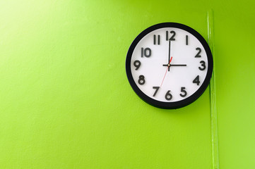 Clock showing 3 o'clock pm on a green wall