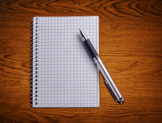 Pen and notebook on a wooden table.