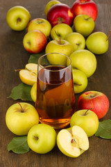 Useful apple juice with apples around on wooden table