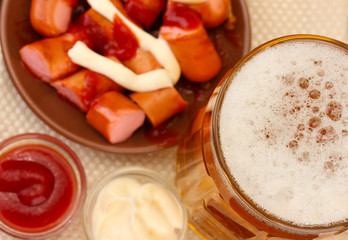 Beer and grilled sausages on wooden background