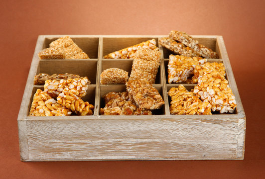 tasty sweets (kozinaki)in wooden crate on brown background