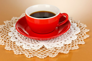 A red cup of strong coffee on beige background