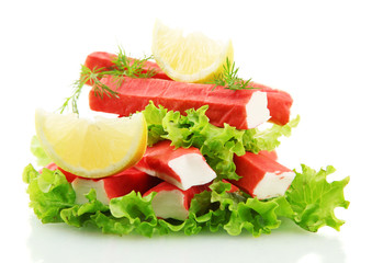 Crab sticks on lettuce leaves with lemon, isolated on white