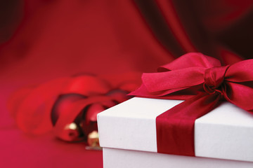 A gift with a red ribbon and heart on red silk