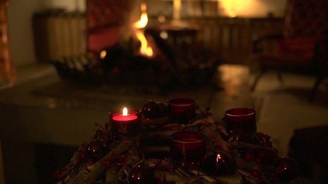 Adventskranz mit einer Kerze und Kaminfeuer
