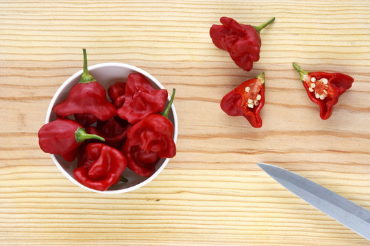 Hot chilli peppers in a bowl over a wooden table.