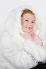 The young beautiful girl in a fur cap on a white background with