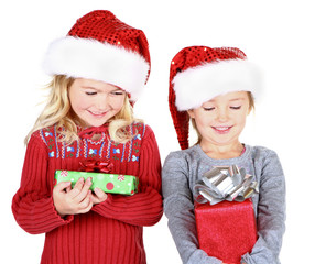 Two children holding presents wearing Santa hats