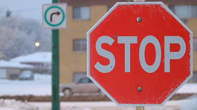 Stop sign and passing cars in winter