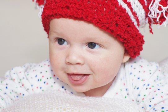 Portrait of the ridiculous baby in a red knitted hat (3 months)