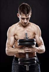 Man with naked torso holding big dumbbell