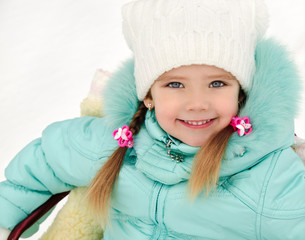 Little girl sitting on her sledge in winter day