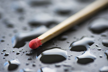 Dry match and raindrops on black metal surface