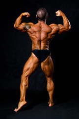 Tanned bodybuilder shows muscles of arms and back