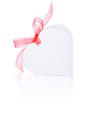 White gift in the form of heart with a bow of red ribbon
