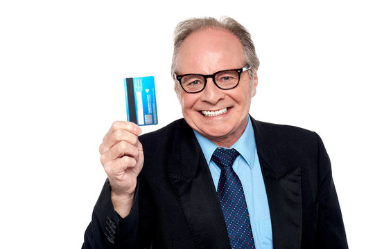 Old man wearing eyeglasses holding up a cash card
