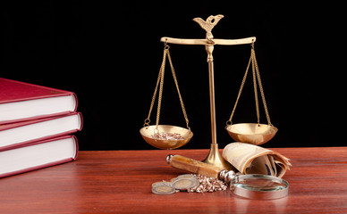 scale of justice on wooden table and black background