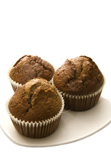 Three gingerbread muffins in cups on a plate.