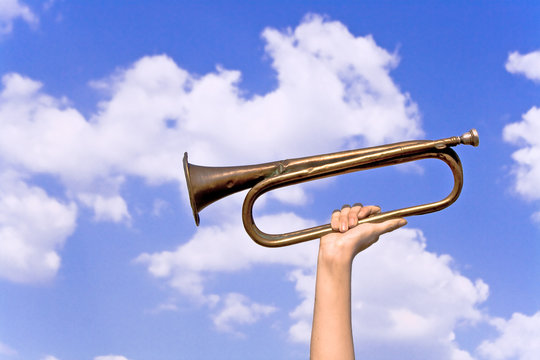 Old army trumpet in hand over blue sky
