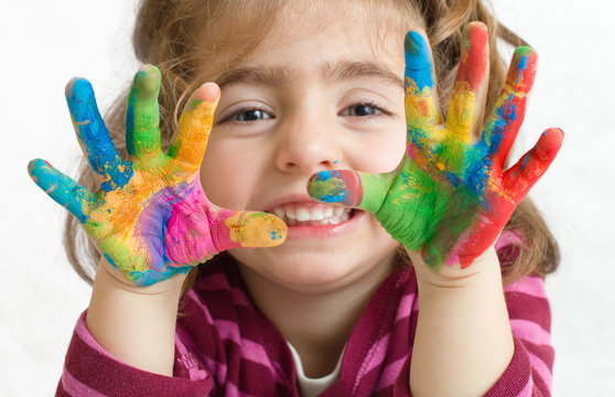 niña preescolar con las manos pintadas