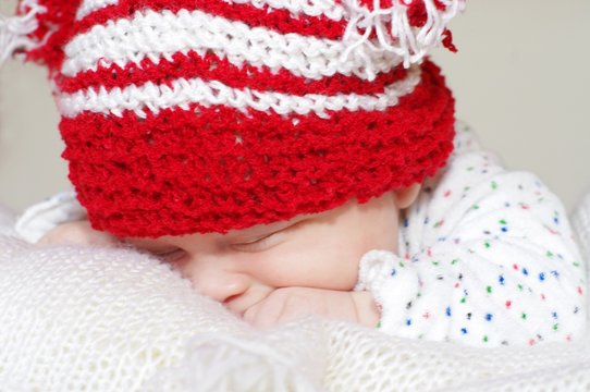 The sleeping baby in a red knitted cap (3 months)