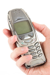 An old worn out cell phone being held over white