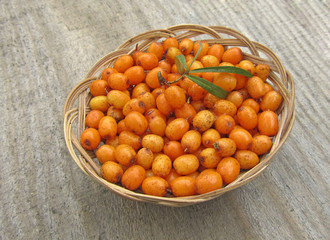 ripe sea buckthorn in basket on wooden background