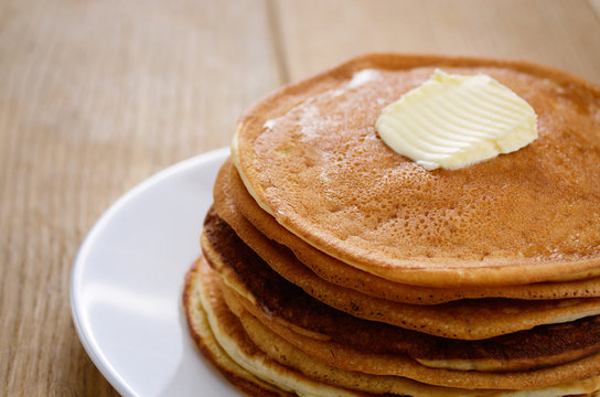 White plate with pankakes stack on the wooden table